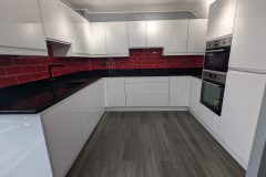 Wren handleless in white gloss, black quartz worktops, red metro tiles and a 4 in 1 tap