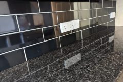 Tiled splashback in gloss black tiles and silver - grey grout