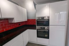Wren handleless in white gloss, black quartz worktops, red metro tiles and a 4 in 1 tap