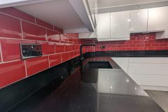 Wren handleless in white gloss, black quartz worktops, red metro tiles and a 4 in 1 tap