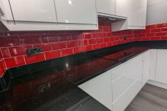 Wren handleless in white gloss, black quartz worktops, red metro tiles and a 4 in 1 tap